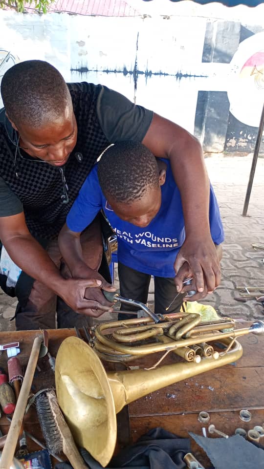 Teaching a child to repair a brass instrument
